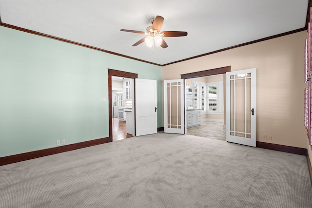 unfurnished bedroom with ceiling fan, french doors, crown molding, ensuite bathroom, and light colored carpet