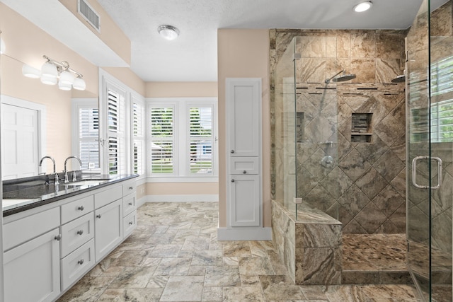 bathroom featuring walk in shower, vanity, and a textured ceiling