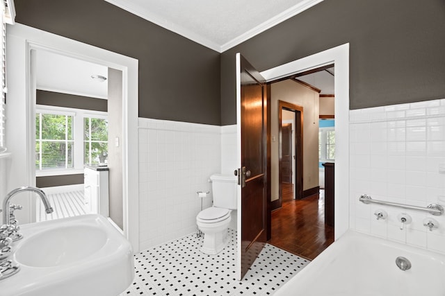 bathroom with sink, a washtub, wood-type flooring, crown molding, and toilet