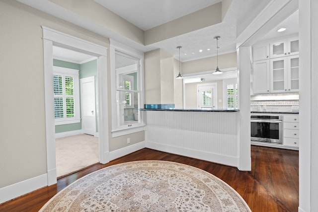 kitchen with pendant lighting, stainless steel oven, dark hardwood / wood-style flooring, and white cabinetry