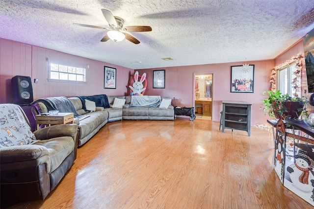 living room with light wood-type flooring, a textured ceiling, and ceiling fan