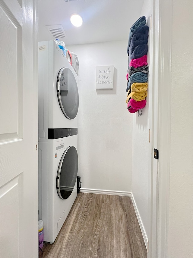 laundry room featuring stacked washer and clothes dryer and light wood-type flooring