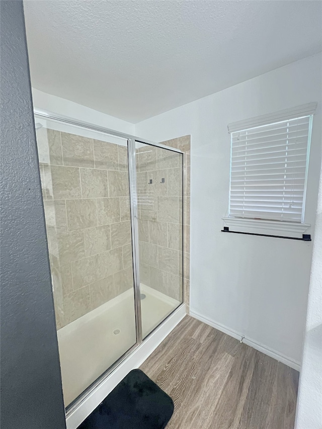 bathroom with a shower with door, hardwood / wood-style floors, and a textured ceiling