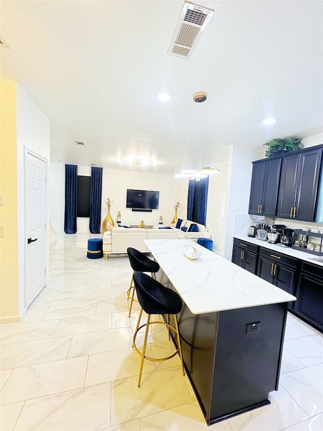 kitchen with pendant lighting, a kitchen bar, a center island, and light stone counters