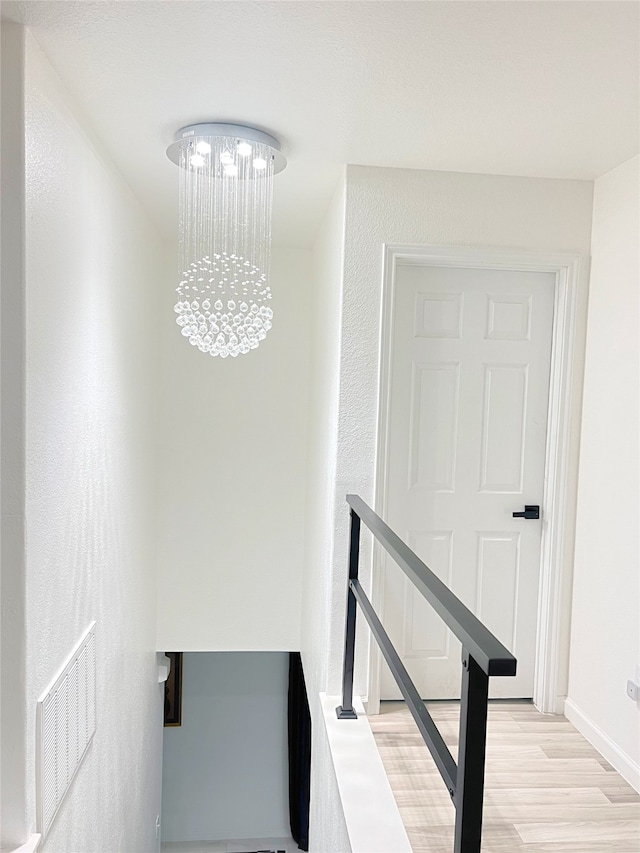 staircase featuring a chandelier and wood-type flooring