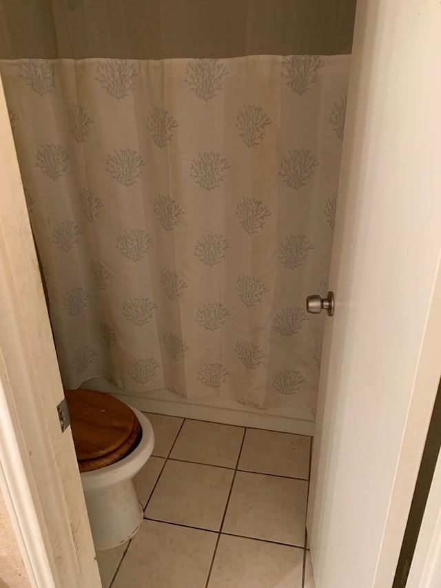 bathroom featuring toilet, walk in shower, and tile patterned floors