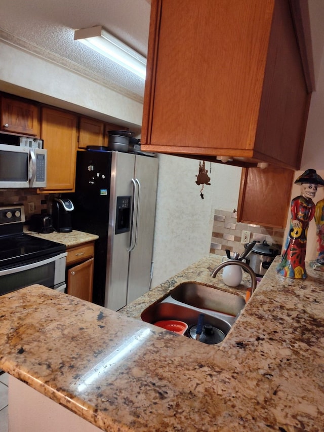 kitchen with sink, decorative backsplash, stainless steel appliances, and a textured ceiling