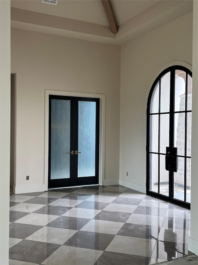 foyer entrance with beam ceiling, french doors, and high vaulted ceiling