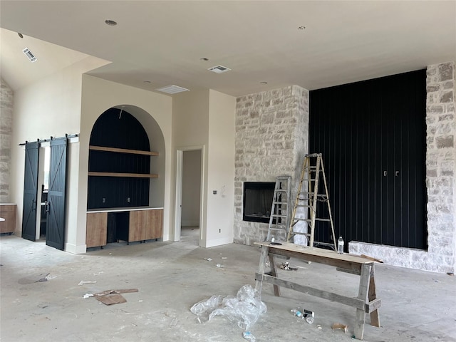 unfurnished living room featuring a fireplace and a barn door