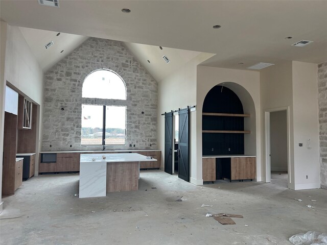 kitchen featuring built in shelves, a kitchen island, a barn door, and a high ceiling