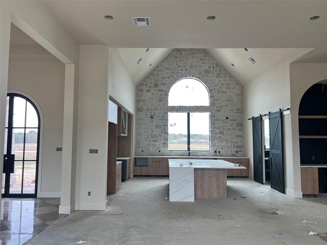 kitchen featuring a towering ceiling, a barn door, and a kitchen island