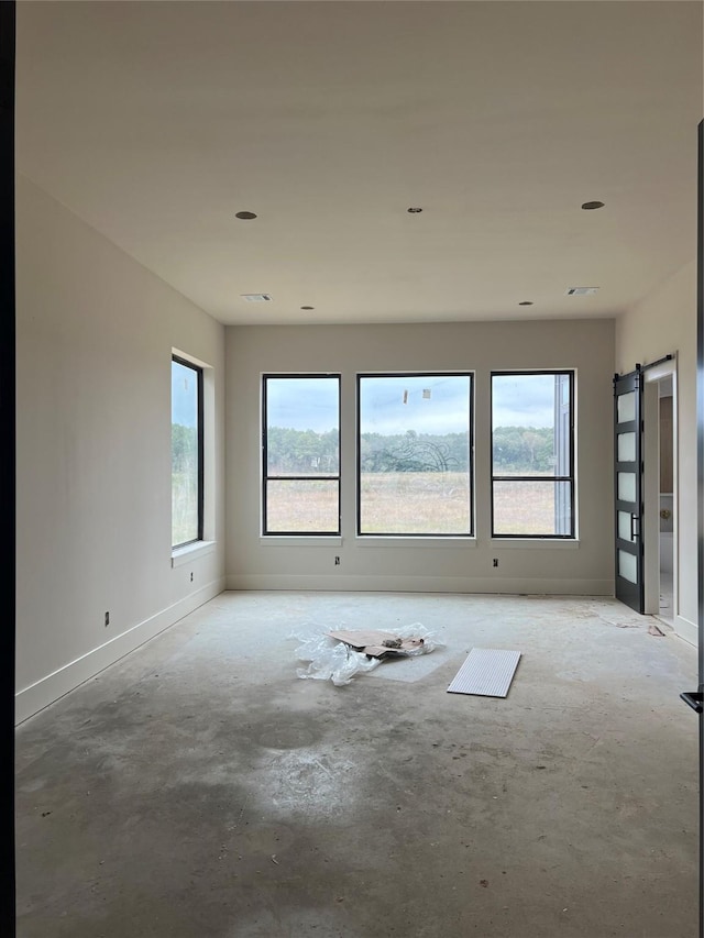 unfurnished room with a barn door and a healthy amount of sunlight