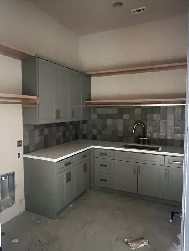 kitchen featuring gray cabinetry, sink, and tasteful backsplash