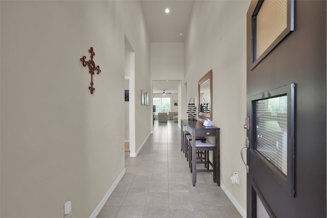 corridor featuring plenty of natural light, a towering ceiling, and light tile patterned floors