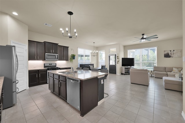 kitchen with stainless steel appliances, an island with sink, pendant lighting, and a healthy amount of sunlight