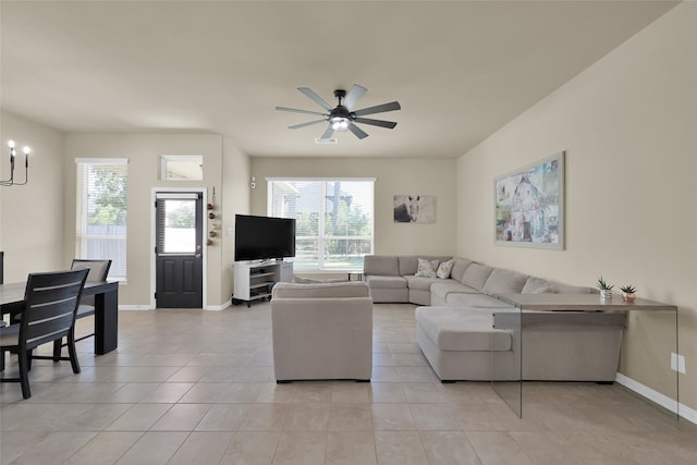 tiled living room with ceiling fan with notable chandelier and a wealth of natural light