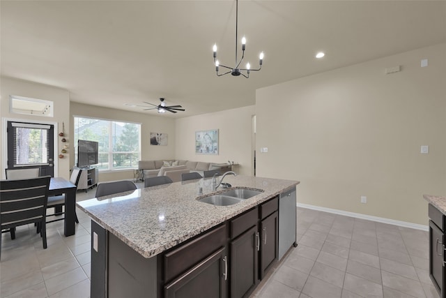 kitchen with light tile patterned flooring, dark brown cabinetry, sink, light stone countertops, and stainless steel dishwasher