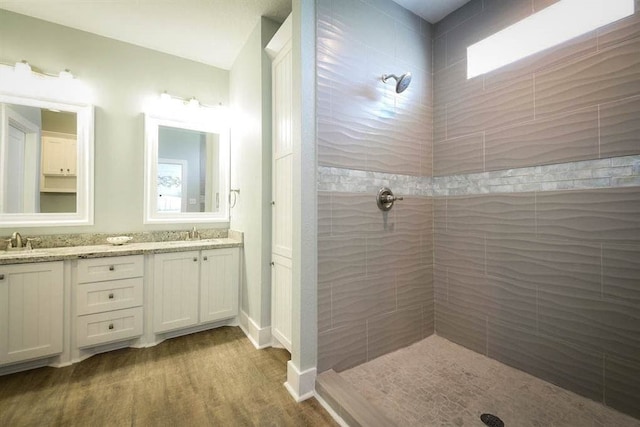 bathroom with hardwood / wood-style floors, a tile shower, and vanity