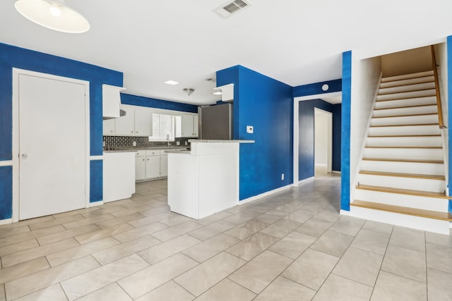 kitchen with light tile patterned flooring, stainless steel refrigerator, sink, backsplash, and white cabinetry