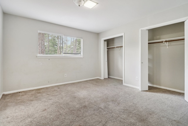 unfurnished bedroom with two closets and carpet flooring