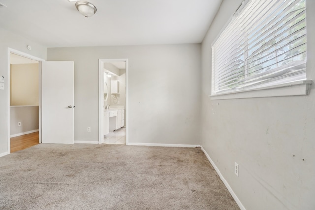 unfurnished bedroom with light colored carpet and connected bathroom