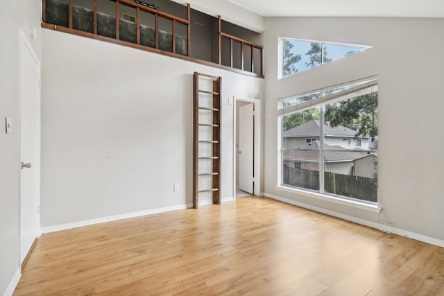 spare room with high vaulted ceiling and hardwood / wood-style floors