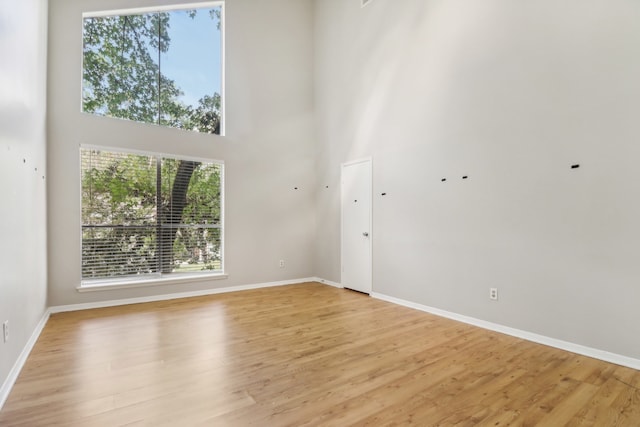 unfurnished living room featuring a high ceiling and light hardwood / wood-style flooring