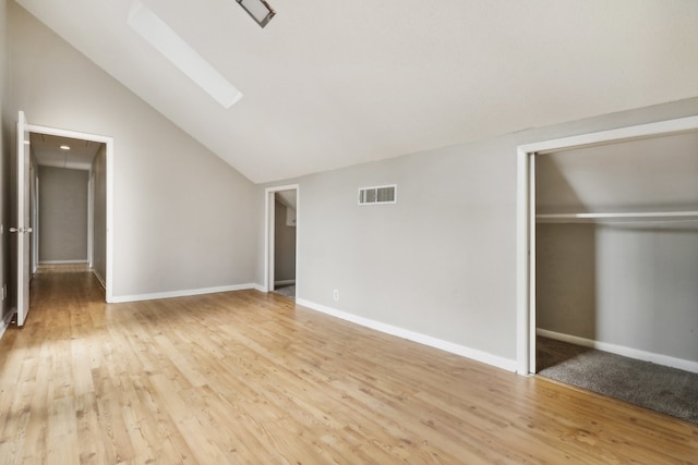 unfurnished bedroom featuring a closet, light hardwood / wood-style flooring, and lofted ceiling with skylight