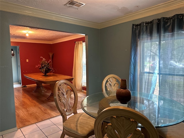 dining room with ornamental molding, light hardwood / wood-style floors, and a textured ceiling