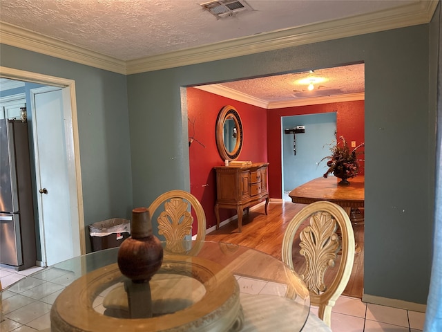 tiled dining area featuring ornamental molding and a textured ceiling