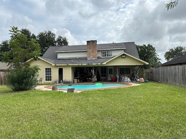 rear view of property with a fenced in pool, a yard, and a patio area