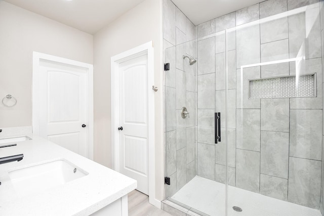 bathroom featuring double vanity, a stall shower, and a sink