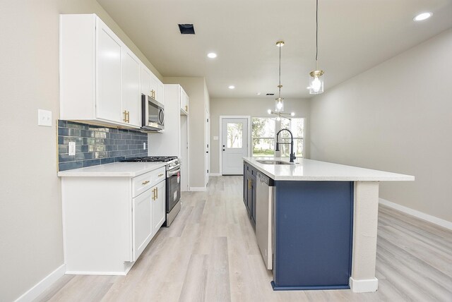 kitchen featuring decorative backsplash, white cabinets, appliances with stainless steel finishes, and a sink