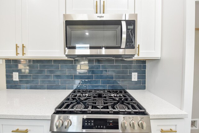 kitchen featuring light stone counters, tasteful backsplash, appliances with stainless steel finishes, and white cabinets