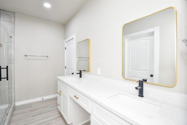 bathroom with a sink, baseboards, double vanity, and a shower stall