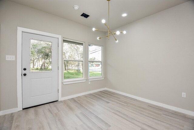 doorway featuring baseboards, a chandelier, and light wood finished floors