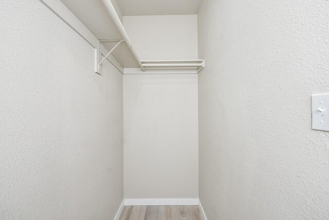 walk in closet with wood finished floors