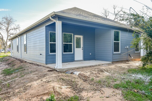 back of property featuring a patio area and roof with shingles