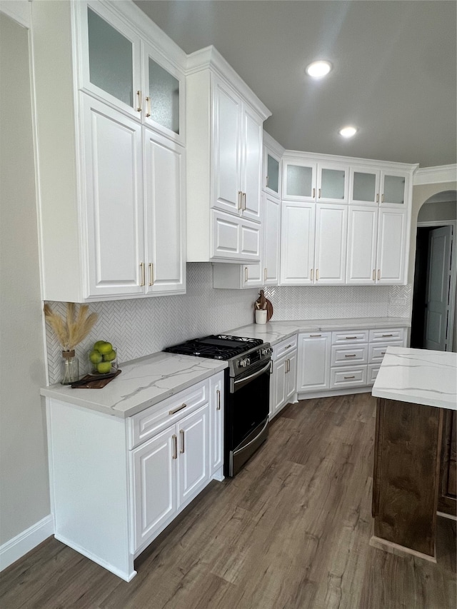 kitchen with dark wood-type flooring, gas range, tasteful backsplash, and white cabinets