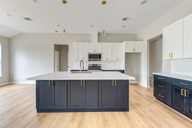 kitchen featuring appliances with stainless steel finishes, hanging light fixtures, white cabinetry, and backsplash