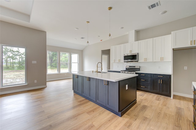 kitchen with stainless steel appliances, pendant lighting, a center island with sink, and white cabinetry