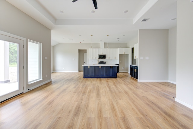 unfurnished living room featuring ceiling fan, light hardwood / wood-style floors, and a raised ceiling