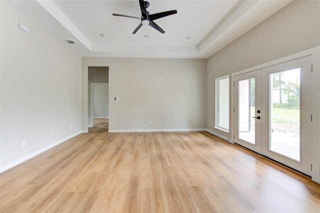 unfurnished room featuring french doors, a tray ceiling, light hardwood / wood-style flooring, and ceiling fan