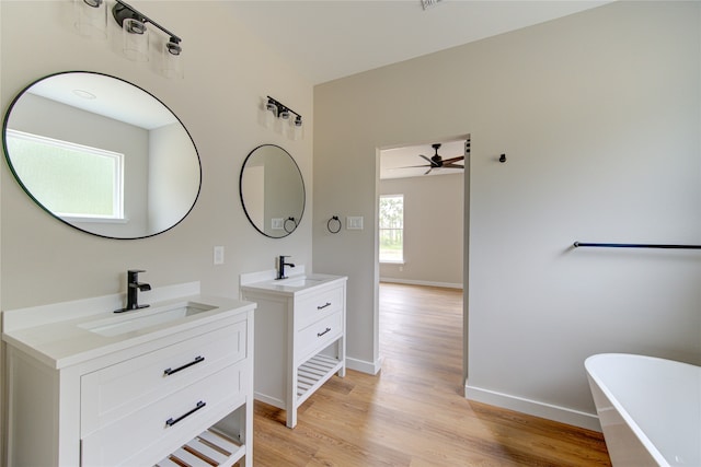 bathroom with wood-type flooring, a tub to relax in, vanity, and ceiling fan