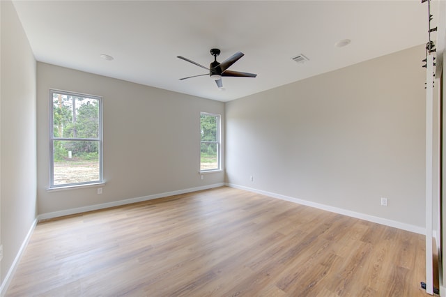 empty room featuring ceiling fan, light hardwood / wood-style flooring, and a healthy amount of sunlight