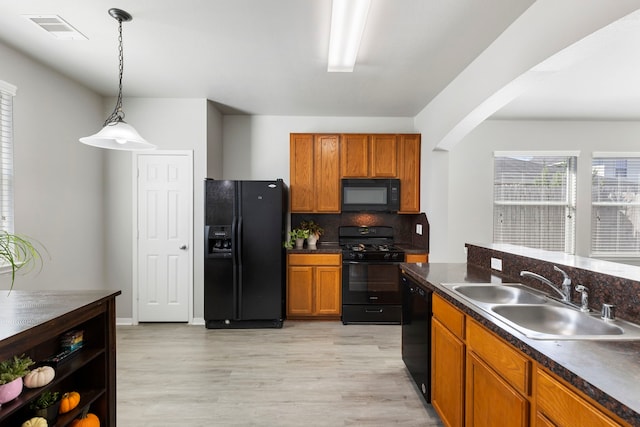 kitchen with black appliances, sink, light wood-type flooring, and hanging light fixtures