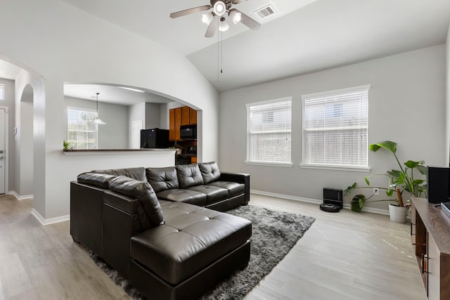 living room featuring a wealth of natural light, lofted ceiling, light hardwood / wood-style floors, and ceiling fan