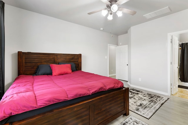 bedroom featuring light hardwood / wood-style flooring, ensuite bath, and ceiling fan