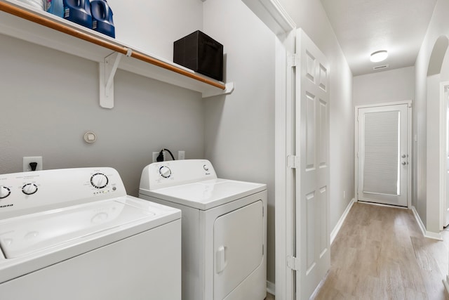 laundry room featuring washing machine and dryer and light wood-type flooring