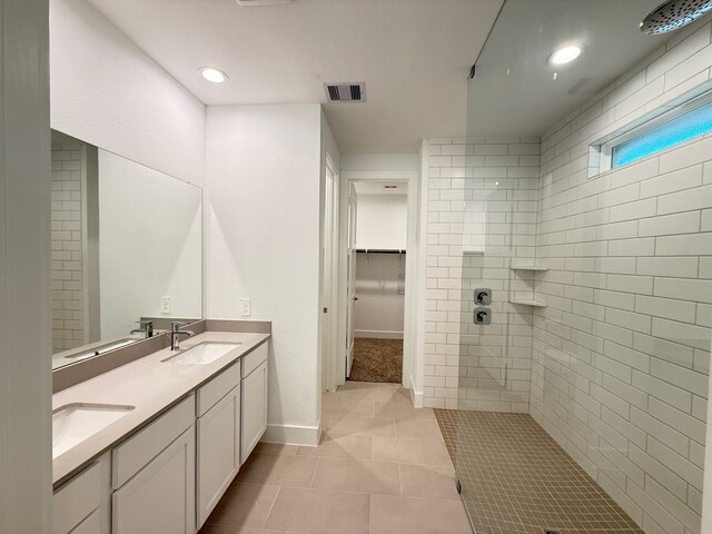 bathroom with tile patterned flooring, vanity, and tiled shower